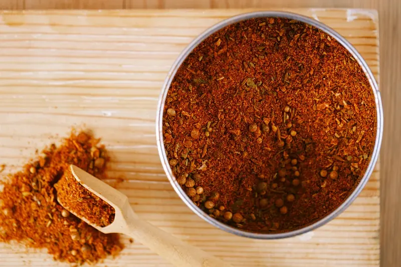 Bowl of red chili spice rub with a wooden scoop