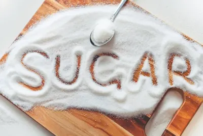 The word sugar written in a pile of white sugar