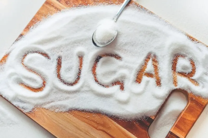The word sugar written in a pile of white sugar