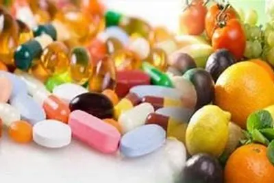 Assorted vitamin capsules surrounded by fresh fruit