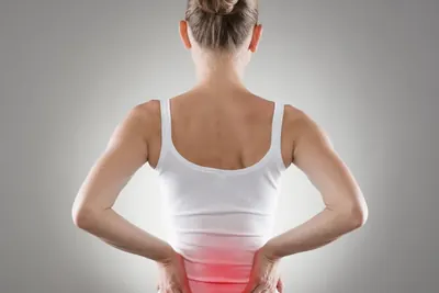 Person holding their lower back near the kidneys
