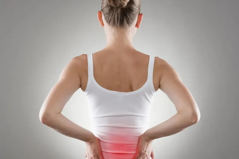 Person holding their lower back near the kidneys